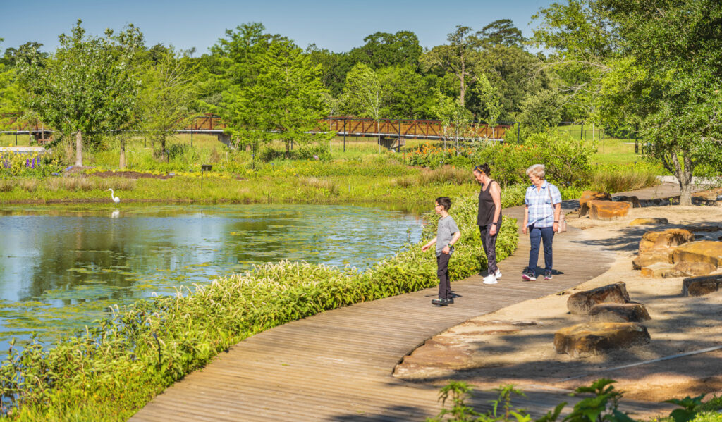 Two women and a child walking beside a body of water in a park