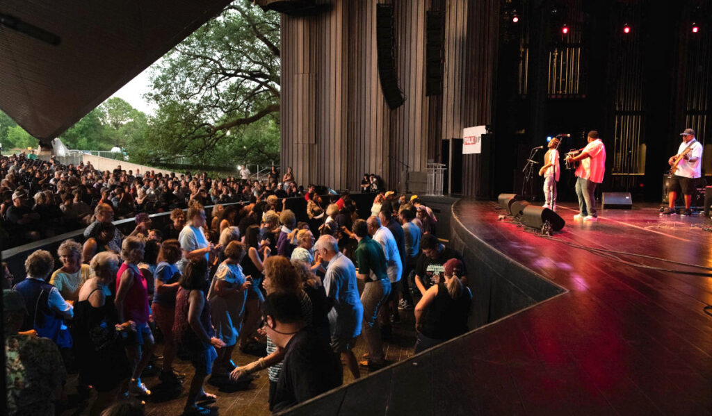 People dance in an orchestra area as zydeco musicians perform on stage