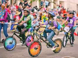 Kids ride bikes that have been decorated with colorful panels