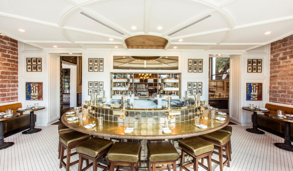 A brightly lit dining room with an oval bar in the center