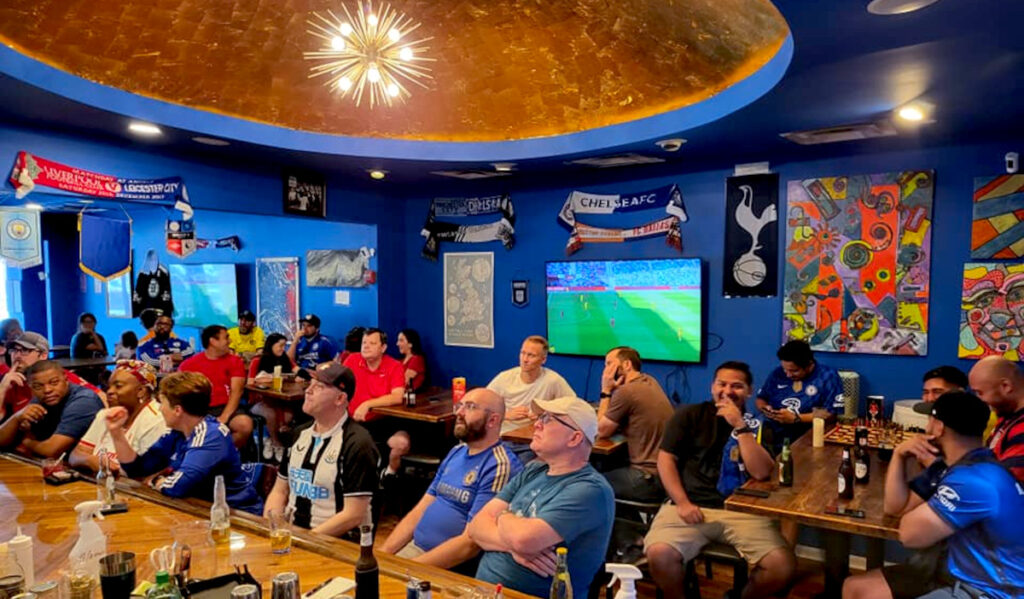 Fans in blue shirts watching soccer on TV