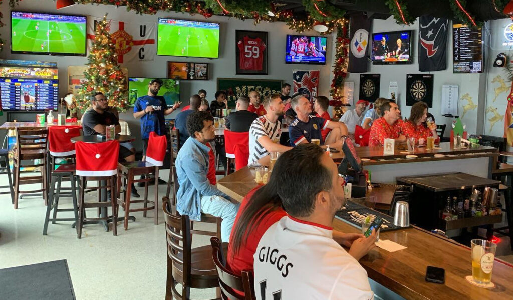 Soccer fans sit in a bar watching soccer on TVs