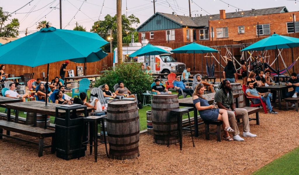 People sitting in an outdoor patio with umbrellas looking at something off-screen