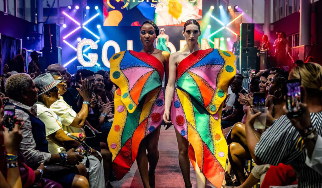 Two runway models walking next to one another, with their clothes creating a rainbow-colored butterfly