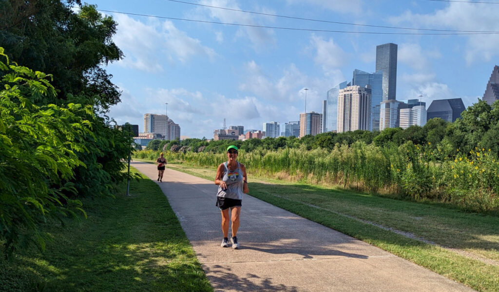 Two runners on a sidewalk with the Downtown skyline behind them