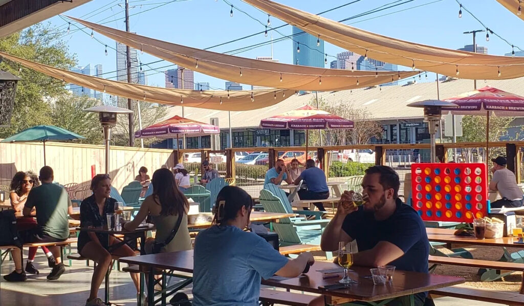 A bar's patio filled with people and the Downtown skyline in the background