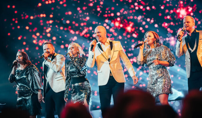 Six members of Rajaton performing on stage in silver formal clothing