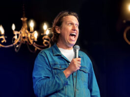 Comedian Pete Holmes performing with a microphone and wide eyes and open mouth