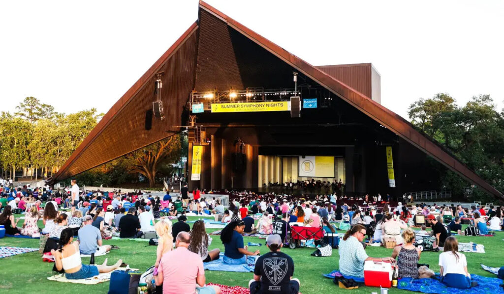 A crowd sitting on blankets and in chairs on the Miller Outdoor Theatre lawn before a performance