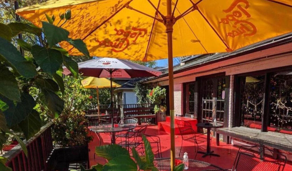 An outdoor patio with tables and umbrellas and a red-painted floor