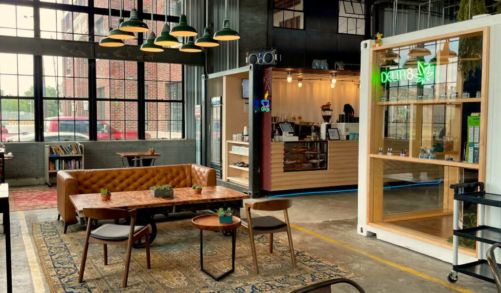 A coffeeshop interior with a couch and chairs, overhanging lights and big windows