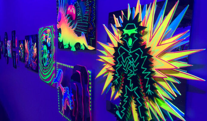 A row of black light art with neon colors in a row at a gallery