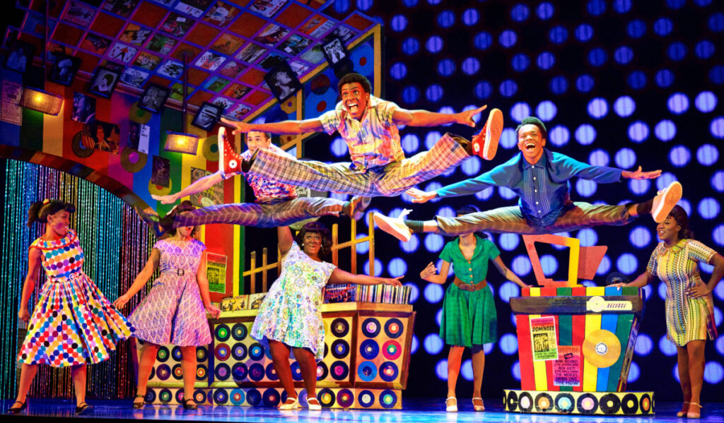 Three male performers leap into splits with colorful backgrounds of records and jukeboxes