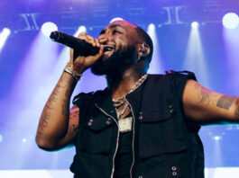 Singer Davido performing with a mic and blue lights behind him