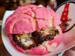 A close up of a barbecue sandwich in a pink concha bread