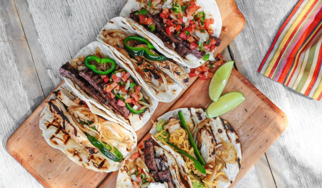 An overhead view of five tacos with different meat and toppings