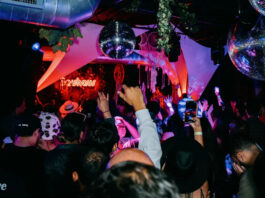 The interior of a night club with a crowd dancing below disco balls