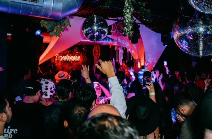 The interior of a night club with a crowd dancing below disco balls