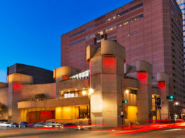 The Alley Theatre exterior at sunset with trails of car taillights through an intersection