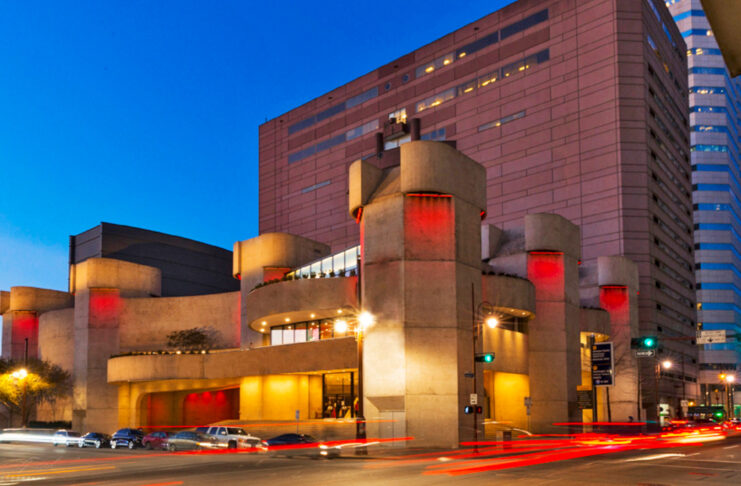 The Alley Theatre exterior at sunset with trails of car taillights through an intersection