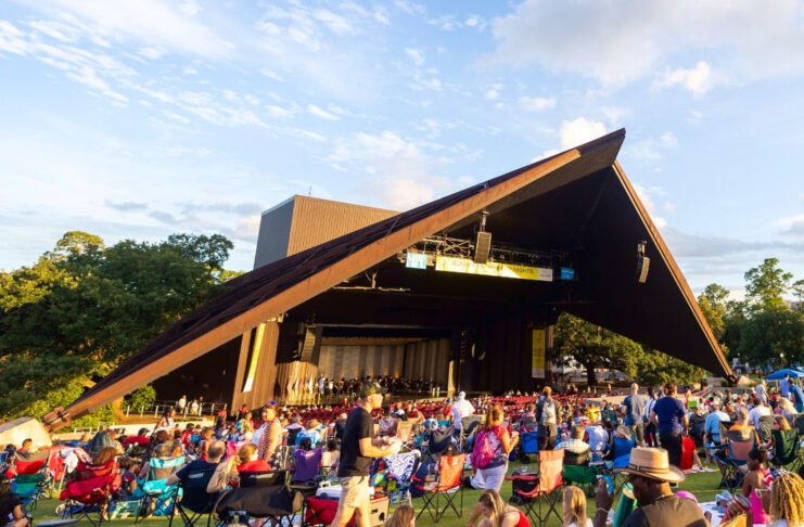 A crowd sitting on blankets and in chairs on the Miller Outdoor Theatre lawn before a performance