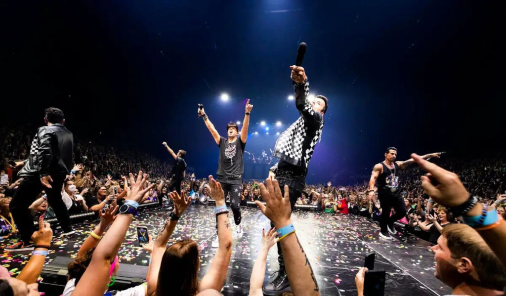 New Kids on the Block performs on stage while fans cheer around them