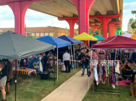 An outdoor market of local vendors with colorful structures overhead