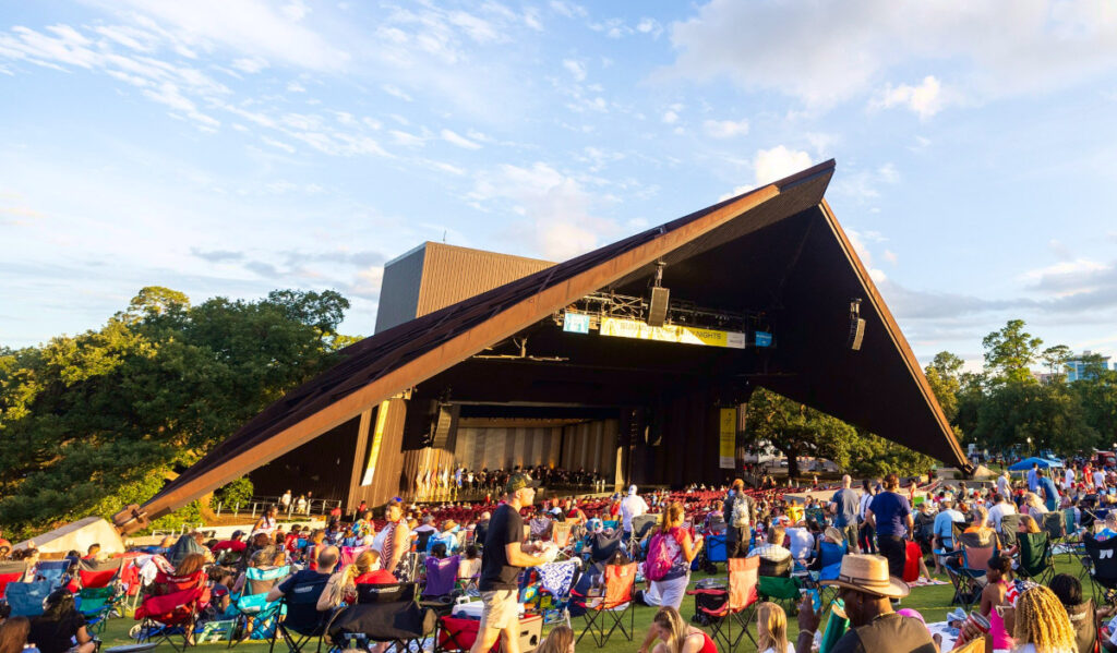 A crowd sitting on blankets and in chairs on the Miller Outdoor Theatre lawn before a performance